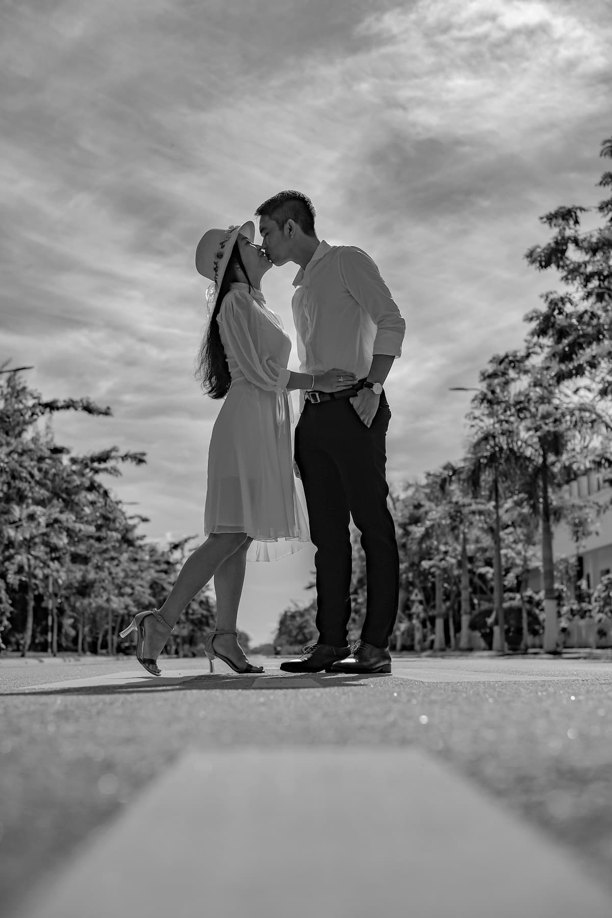 Đôi trẻ hôn nhau giữa con đường hai bên hàng cây