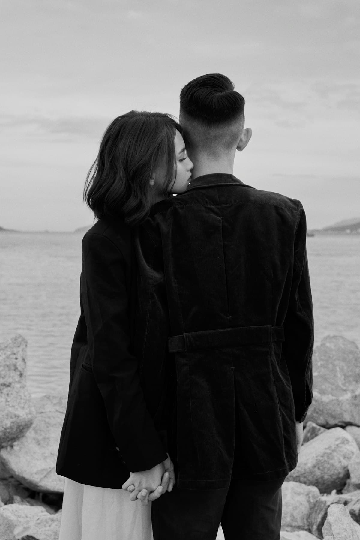 Cô gái tựa đầu vào vai chàng trai, hai người nhìn ra mặt nước