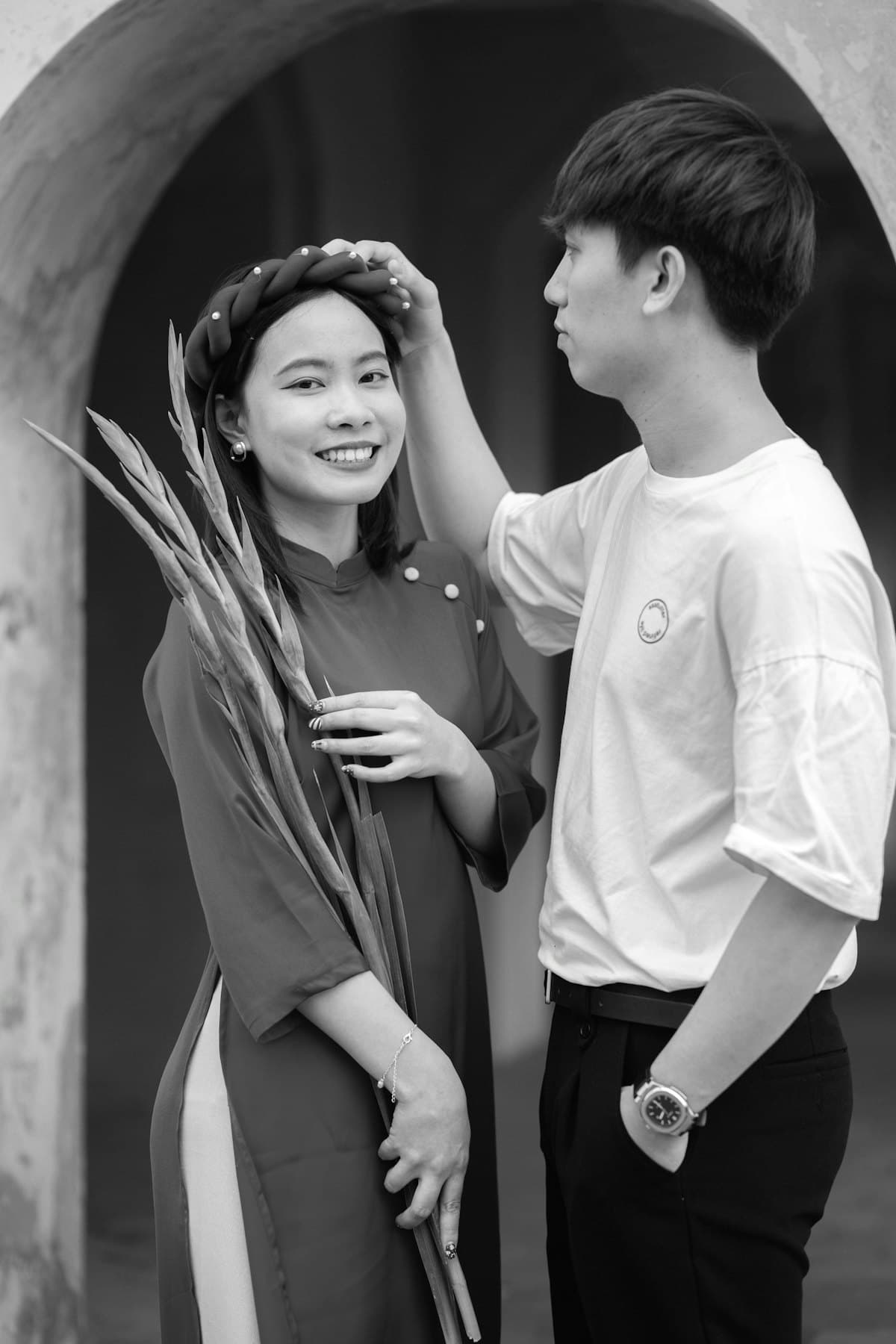 Chàng trai cài bông hoa lên tóc cô gái mặc áo dài ôm bó lay ơn